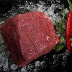 Rosbief uit de verpakking in ijs neergelegd, samen met bieslook en een peper.